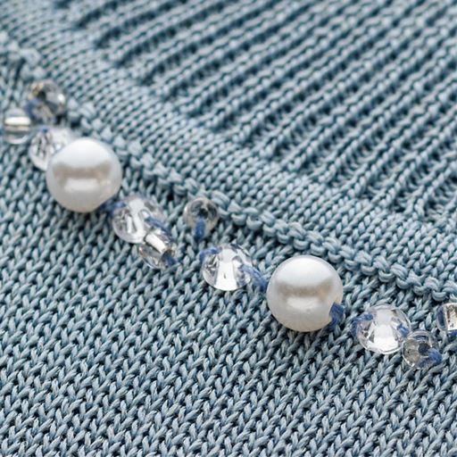 裾に丸みのあるねボレロ調のトッパーは、透け感のある軽やかな編地。衿のビジューがきらめく4分袖プルオーバーは、2本取りの糸で透けを抑えました。