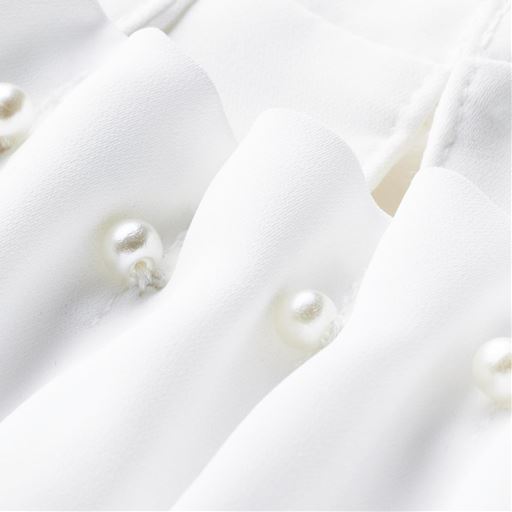 顔まわりに華やぎを添える衿元のパール調ボタン