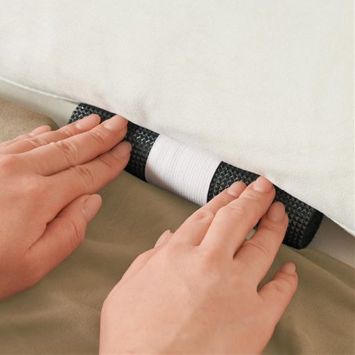 固定パイプを生地裏のゴムバンドに通してソファの隙間に押し込みます。